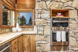 Kitchen featuring backsplash, double oven, and tile counters