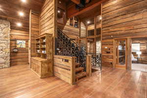 Stairs with hardwood / wood-style floors, a towering ceiling, and beamed ceiling