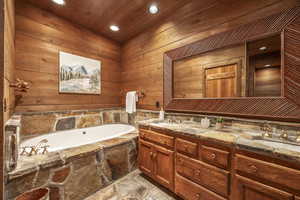 Bathroom with vanity, a bathtub, wooden walls, and wood ceiling