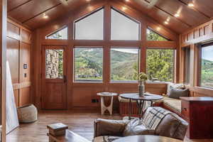 Living room with wood walls, vaulted ceiling, and light wood-type flooring