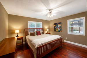 Bedroom with ceiling fan, dark hardwood / wood-style flooring, and a textured ceiling