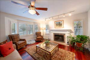 Living room with dark hardwood / wood-style flooring, ceiling fan, and a healthy amount of sunlight