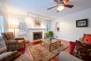 Living room with hardwood / wood-style floors, ceiling fan, and a tile fireplace