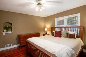 Bedroom with ceiling fan, dark hardwood / wood-style floors, and a textured ceiling