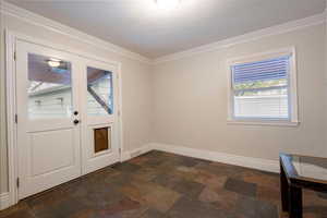 Doorway with a textured ceiling and ornamental molding