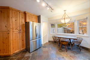 Kitchen with stainless steel fridge, light brown cabinets, and decorative light fixtures