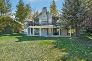 Back of house featuring a yard, a balcony, and a patio area