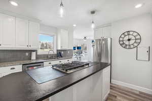 Kitchen featuring decorative light fixtures, white cabinetry, sink, and appliances with stainless steel finishes