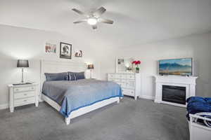 Carpeted bedroom featuring vaulted ceiling and ceiling fan