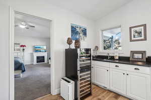 Kitchen featuring ceiling fan, sink, light hardwood / wood-style floors, vaulted ceiling, and white cabinets