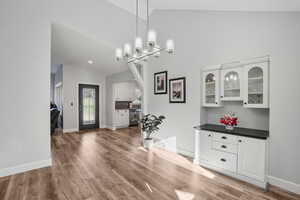 Dining space with high vaulted ceiling, a notable chandelier, and wood-type flooring