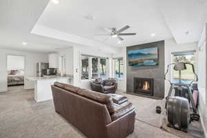 Living room with a tile fireplace, light colored carpet, and plenty of natural light