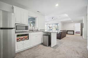 Kitchen with sink, kitchen peninsula, light carpet, white cabinets, and appliances with stainless steel finishes