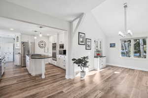 Kitchen featuring stainless steel appliances, decorative light fixtures, white cabinetry, hardwood / wood-style floors, and a kitchen island