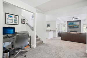 Home office with a tile fireplace, ceiling fan, and light colored carpet