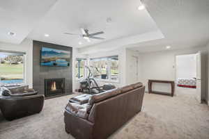 Carpeted living room featuring a fireplace, a textured ceiling, and ceiling fan