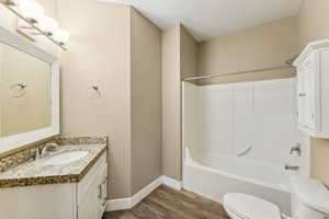 Full bathroom featuring toilet, vanity, shower / bathtub combination, and hardwood / wood-style flooring