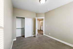 Unfurnished bedroom with washer / dryer, carpet floors, and a closet