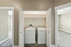 Laundry area featuring washing machine and clothes dryer and dark carpet