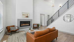 Living room featuring a towering ceiling, light hardwood / wood-style floors, and an inviting chandelier