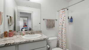 Bathroom with vanity, toilet, and a shower with shower curtain