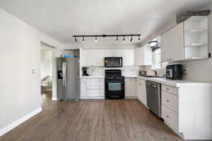 Kitchen featuring white cabinetry, sink, black appliances, dark hardwood / wood-style floors, and tile counters