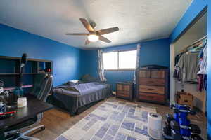 Bedroom featuring a textured ceiling, ceiling fan, and dark hardwood / wood-style floors