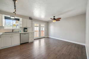 Kitchen with dark wood-type flooring, french doors, white cabinets, and stainless steel dishwasher