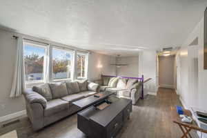 Living room featuring a textured ceiling, dark hardwood / wood-style floors, and ceiling fan