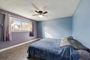 Bedroom with ceiling fan, parquet flooring, and a textured ceiling