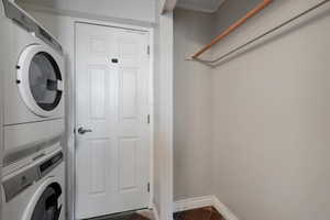 Clothes washing area with dark tile patterned floors and stacked washer / dryer