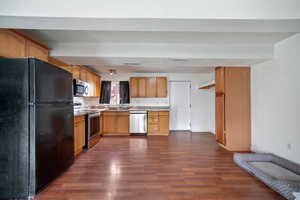 Kitchen featuring light brown cabinetry, dark hardwood / wood-style flooring, stainless steel appliances, and sink