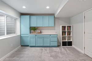 Bar with blue cabinetry and light carpet