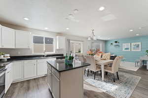 Kitchen featuring wood walls, sink, white cabinets, pendant lighting, and light lvp flooring