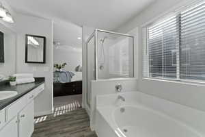 Primary Suite with vanity, vinyl floors, and separate shower and tub