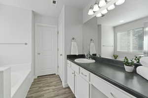 Primary suite vanity, a relaxing separate tub and shower with vinyl flooring