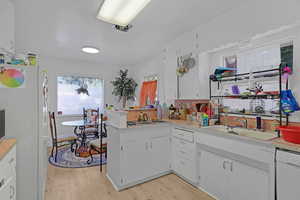 Kitchen with light hardwood / wood-style flooring, white cabinets, white appliances, and sink