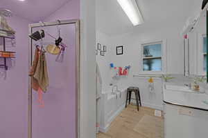 Bathroom with a tub, vanity, vaulted ceiling, and hardwood / wood-style flooring