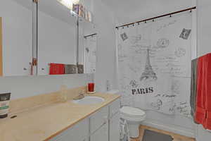 Full bathroom featuring tile patterned flooring, vanity, shower / bath combination with curtain, and toilet