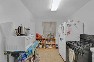 Kitchen featuring black gas range oven and white refrigerator