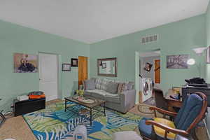 Living room with carpet and independent washer and dryer