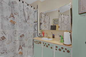 Bathroom with backsplash, vanity, and a shower with shower curtain