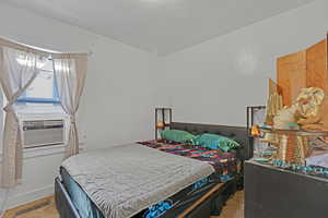 Bedroom with light colored carpet and cooling unit