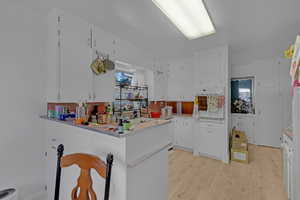 Kitchen with oven, white cabinets, light wood-type flooring, and tasteful backsplash