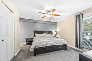 Carpeted bedroom with ceiling fan and a closet