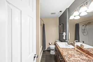 Full bathroom with tile patterned flooring, vanity, toilet, and shower / tub combo with curtain