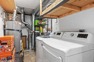 Clothes washing area featuring washing machine and dryer and water heater. Separate room next to home entry way.