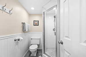 Bathroom featuring tile patterned floors, a shower with door, and toilet