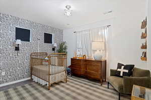 Carpeted bedroom with a textured ceiling and a crib