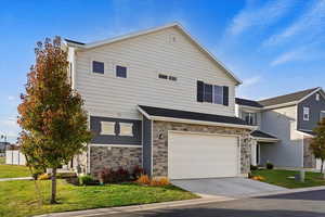 View of front facade with a front lawn and a 2 car garage and driveway